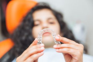 teen girl holding braces, dentist puts braces on girl. dental care and orthodontic concept.